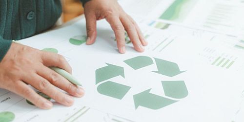 Un opérateur devant un document imprimé représentant le ruban de Möbius, logo universel des matériaux recyclables